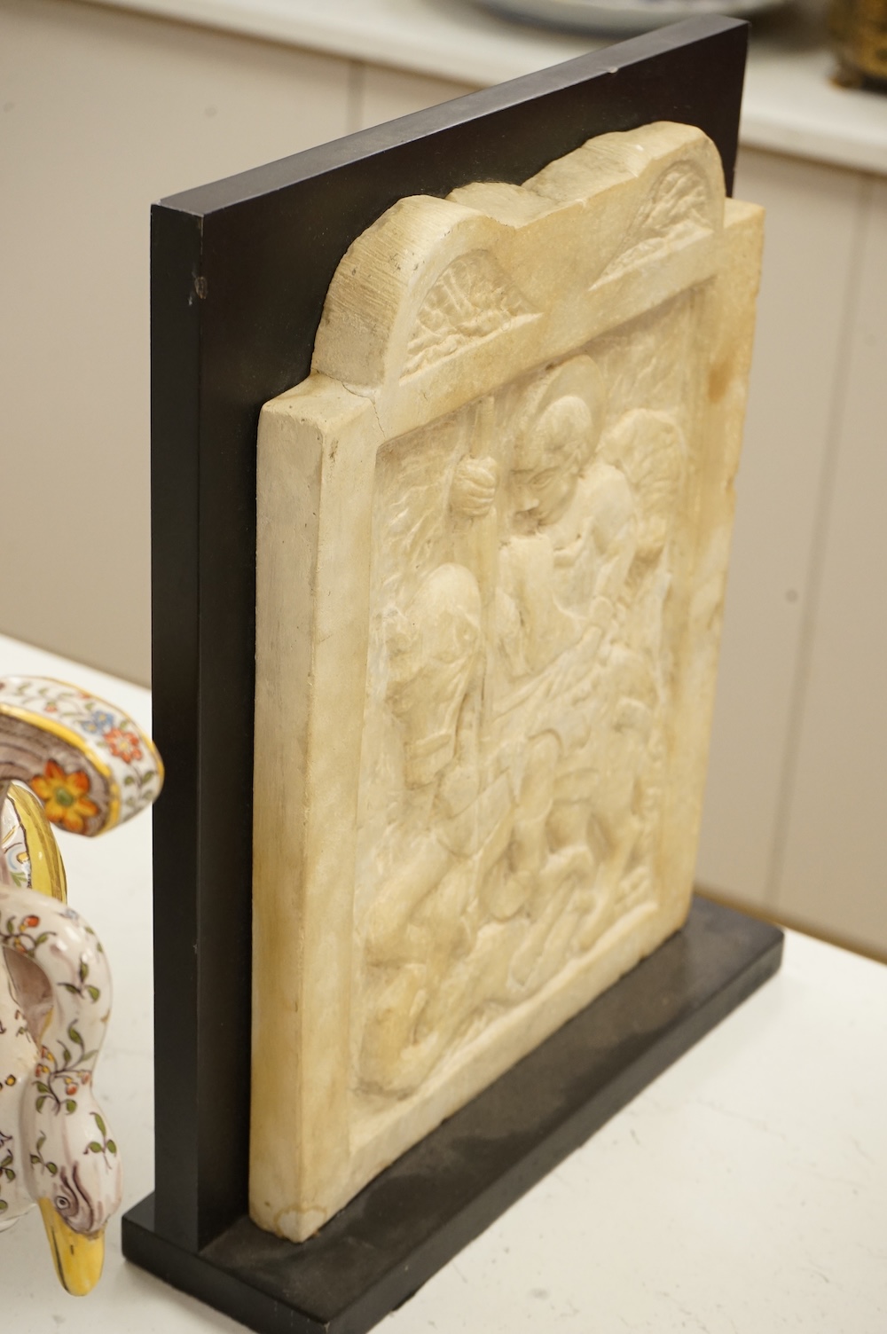 A 19th century carved white marble panel depicting Saint George and the dragon, on stand, 37cm